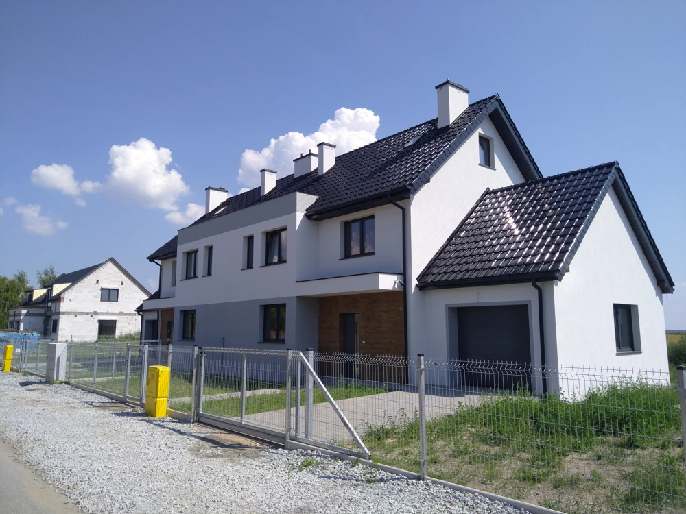 Nowoczesny bliźniak z białą elewacją i czarnym dachem – Budowa domów pod klucz